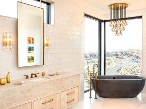 A beautiful white bathroom with golden accents and a dark bathtub. 